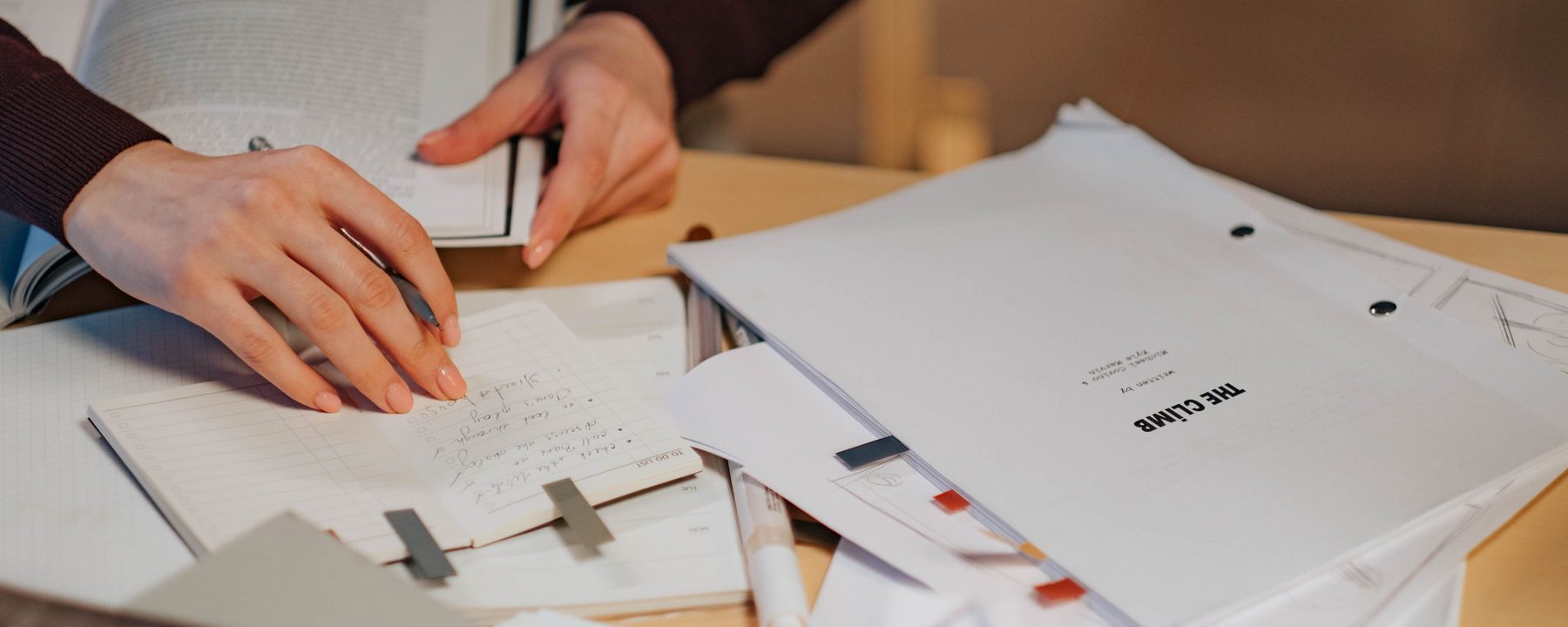Hands writing among documents on a desk