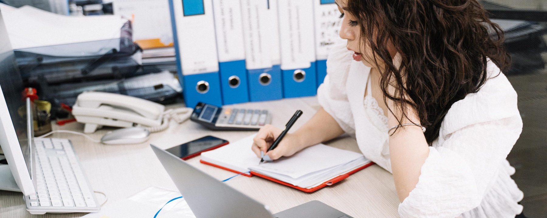 A desk with ring binders, a telephone and a notebook