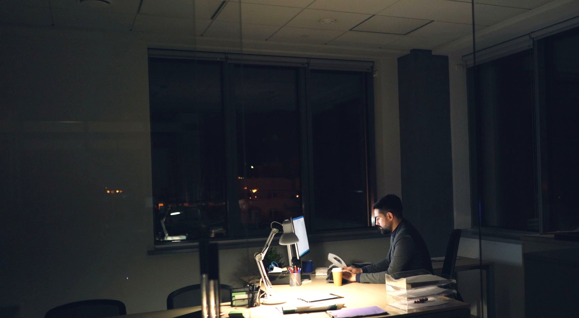 A lit office at night with one person still working at a desk