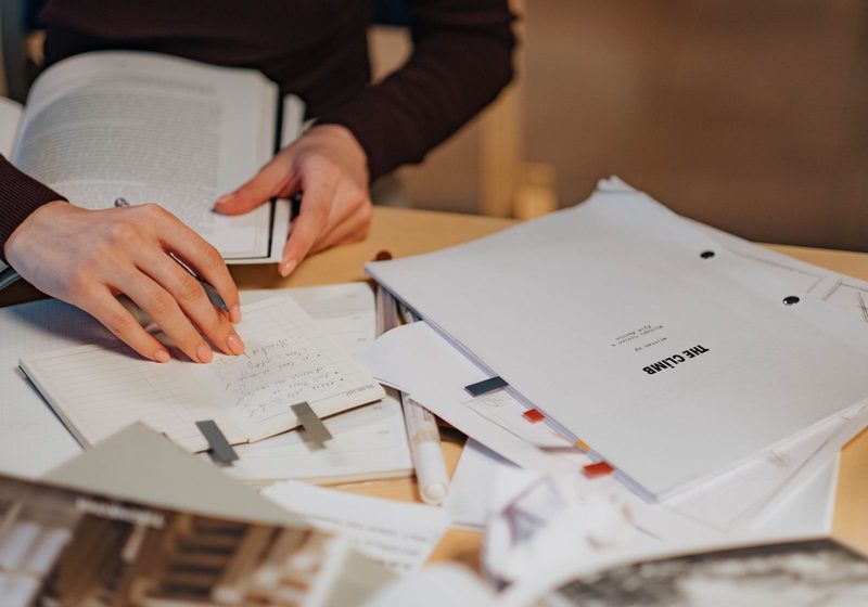 Hands writing among documents on a desk