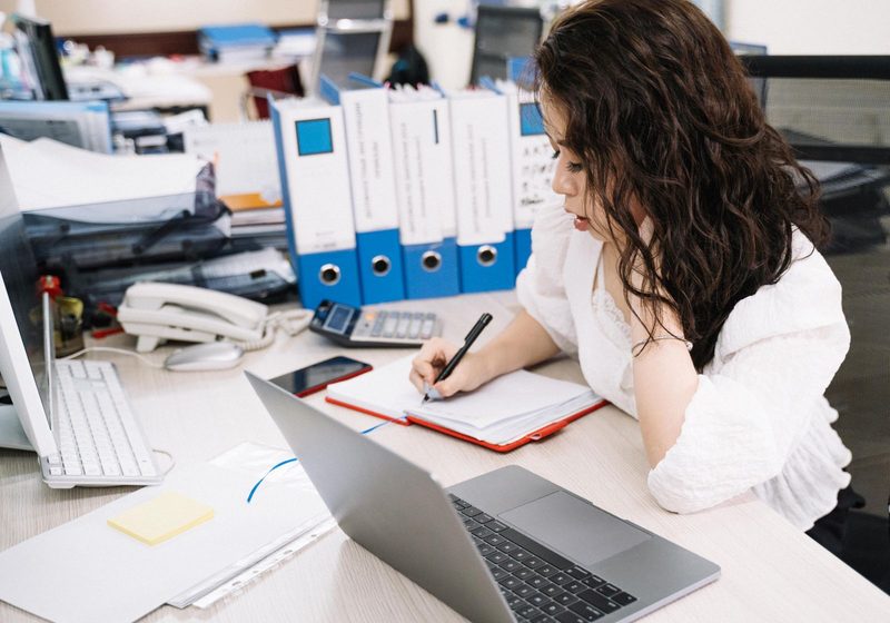 A desk with ring binders, a telephone and a notebook